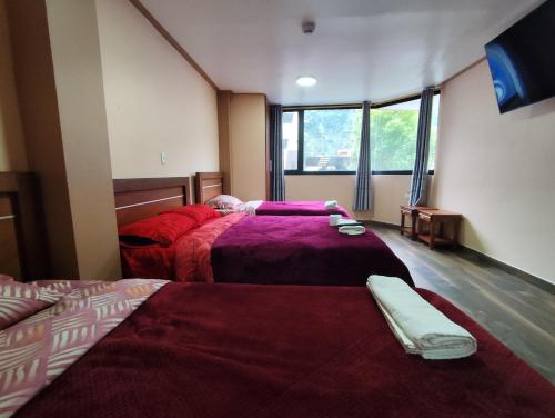 a bedroom with two beds with red comforters at Hostal California AC-DC in Baños