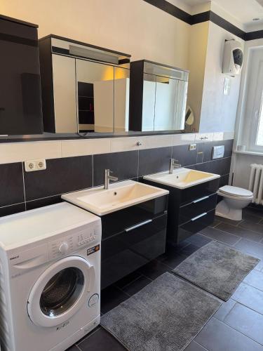 a bathroom with two sinks and a washing machine at Wohnen inklusive Fitness & Wellness in Dessau