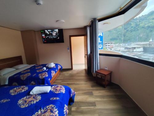 a hotel room with two beds and a window at Hostal California AC-DC in Baños