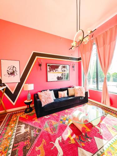 a living room with a black couch and a pink wall at Dolly's Glam Getaway - Glittering Gem Near Broadway in Nashville