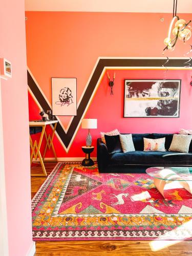 a living room with orange walls and a black couch at Dolly's Glam Getaway - Glittering Gem Near Broadway in Nashville