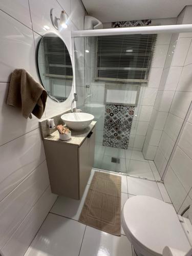 a white bathroom with a sink and a toilet at Apartamento pé na areia in Santos