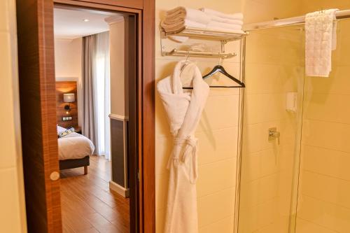 a bathroom with a shower and a robe at Lounis Hôtel by Atlantis in Oran