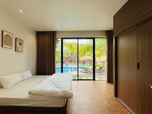 Un dormitorio con una cama y vistas a una piscina. en Villa is close to nature, en Xóm Bình Nguyên