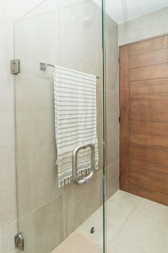 a shower with a glass door and a towel at Brand New Condo near beach in Santa Cruz Huatulco