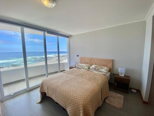 a bedroom with a bed with a view of the ocean at Deapartamento al Océano-Primer Linea ,Península Cavancha in Iquique
