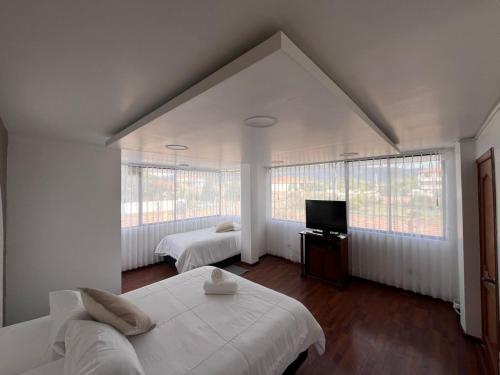 a bedroom with two beds and a flat screen tv at Hesed Hospedaje in Riobamba