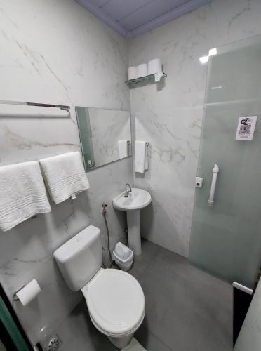 a white bathroom with a toilet and a sink at Pousada do Leô in Mangaratiba