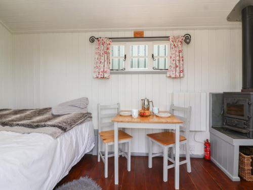 a bedroom with a bed and a table with a stove at The Shepherds Hut in Nettleton