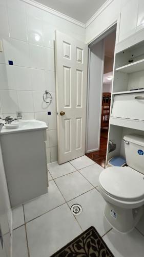 a white bathroom with a toilet and a sink at Cabañas Coquimbo in Coquimbo