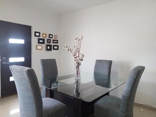 a glass table with chairs and a vase with flowers at Departamento familiar único! BIENVENIDOS! in Torreón