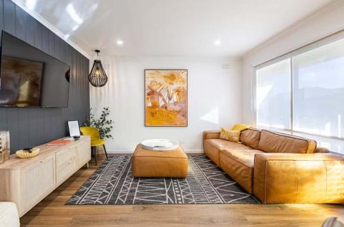 a living room with a brown couch and a tv at Ocean Gioia - Stroll to shops and beach in Ocean Grove