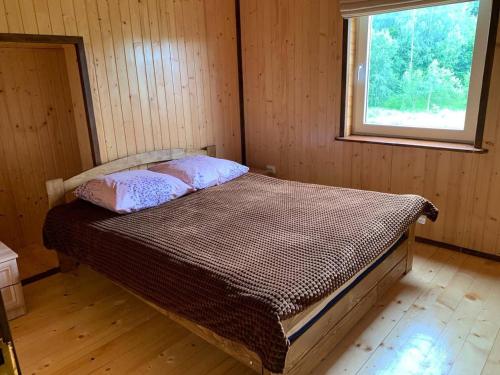 ein Bett in einem Holzzimmer mit Fenster in der Unterkunft Армаден in Slawske