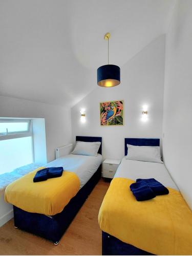 two beds with yellow and blue covers in a room at Blue Door Apartments in Dover