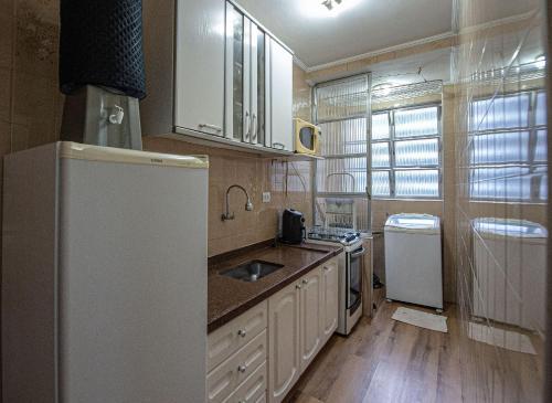 a kitchen with a white refrigerator and a sink at Conforto familiar – Wi-Fi veloz e 1 min da praia in Santos