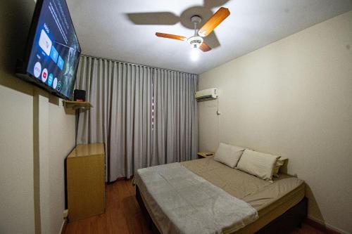 a bedroom with a bed with a ceiling fan and a tv at Conforto familiar – Wi-Fi veloz e 1 min da praia in Santos