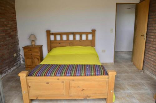 a bedroom with a wooden bed with a yellow blanket at Cabaña El Balcón in La Estancia