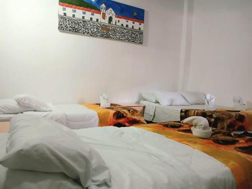 a room with three beds and a painting on the wall at La tranquera hotel in Villa de Leyva