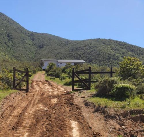 a dirt road with a fence and a house on a hill at Casa parcela en Quilimari a 20 minutos de playa Pichidangui in Quilimarí
