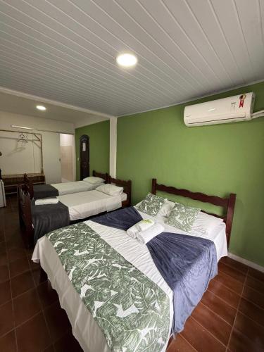 two beds in a room with green walls at Pousada Lisamar in Mangaratiba