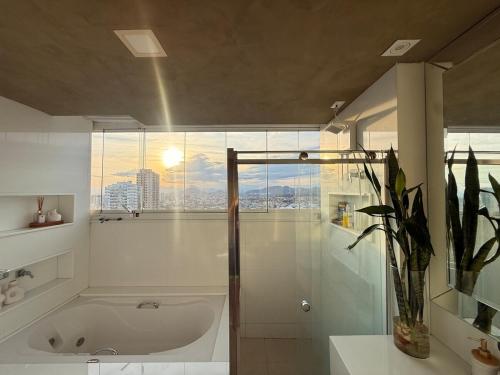 a bathroom with a bath tub and a window at Cobertura dúplex frente mar Sunset in Vila Velha