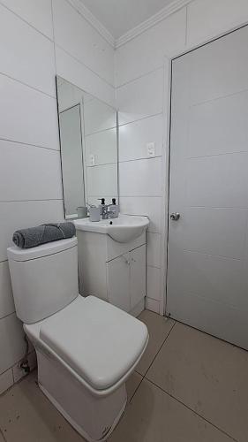 a white bathroom with a toilet and a sink at Hospedaje - Apart Hotel Las Higueras Talcahuano in Talcahuano