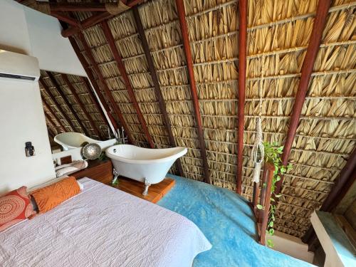 une salle de bain avec un lit et une baignoire dans une paillote dans l'établissement Aldea Kanaloa Hotel Puerto Escondido, à Brisas de Zicatela