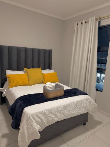 a bed with yellow pillows and a gray headboard at Charlsi luxury apartment 2 in Midrand