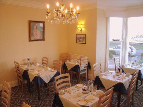 a dining room with tables and chairs and a chandelier at Britannia Guest House in Llandudno