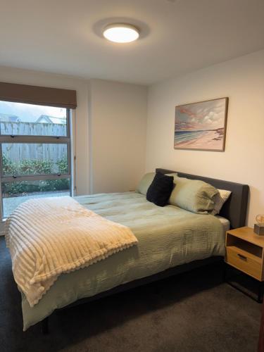 Un dormitorio con una cama con una ventana grande. en Plantation apartment, en Wanaka