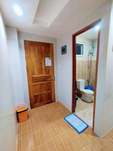a bathroom with a toilet and a wooden door at Eme's Apartelle in General Luna