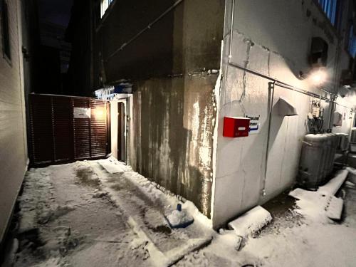 an alley with snow on the side of a building at Tomoeドットコム 5 Cafe and Stay in Hakodate