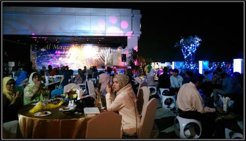 a group of people sitting at tables in front of a stage at Al Meroz Hotel Bangkok - The Leading Halal Hotel in Bangkok