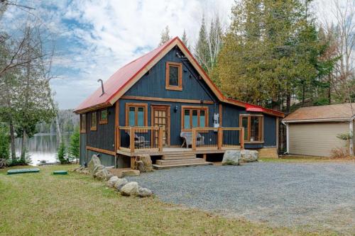 a blue house with a red roof at Chalet familial forêt & kayak in Nominingue