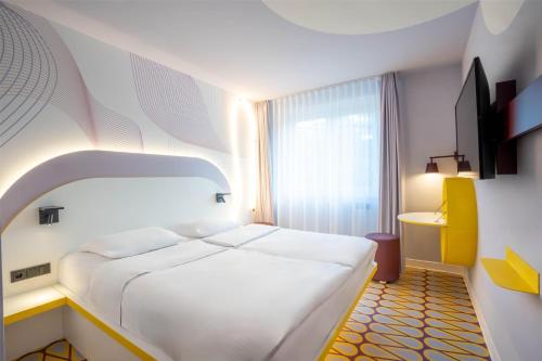 a bedroom with a large white bed and a window at Prize by Radisson, Osnabruck in Osnabrück