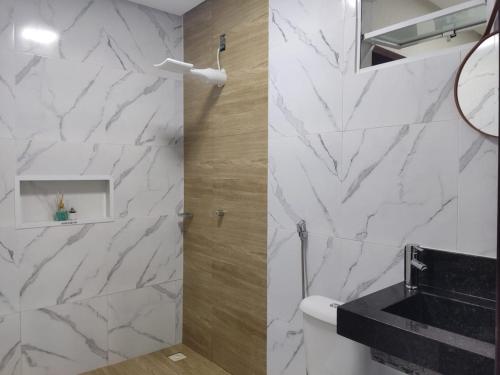 a bathroom with white marble walls and a sink at Casa de condomínio em Paripueira in Paripueira