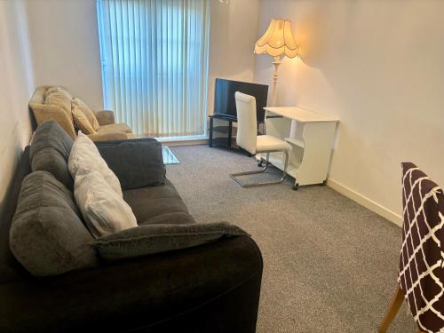 a living room with a couch and a desk at The Flat in Monmore Green