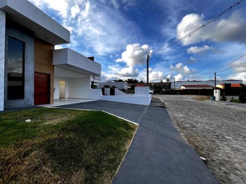 a modern house with a sidewalk next to a street at Casa de condomínio em Paripueira com piscina e perto da praia in Paripueira