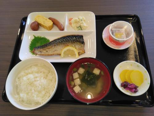 Una bandeja con pescado y arroz y otros alimentos. en Joy Park Hotel 種子島, en Nishinoomote
