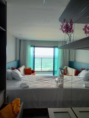 Un dormitorio con dos camas y una gran ventana. en Studio Luxuoso vista Mar, en Salvador
