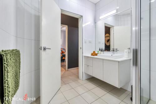 a white bathroom with a sink and a mirror at The Skyline Lookout 2 Bd Apt in Stuart Park