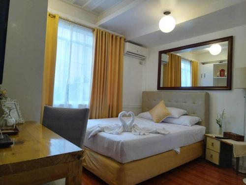 a bedroom with a bed and a desk and a mirror at Makati Riverside Inn in Manila