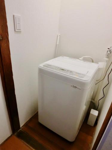 a small white refrigerator in a corner of a room at 4mins from sky tree Sumida area 3rooms Wifi in Tokyo