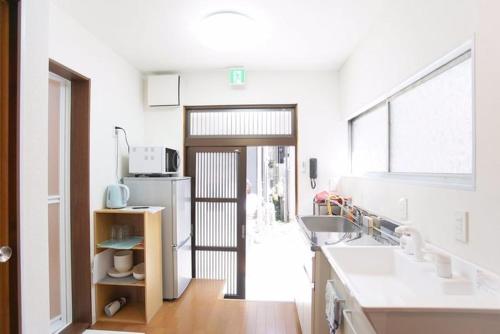 a kitchen with a door open to a kitchen with white counters at 4mins from sky tree Sumida area 3rooms Wifi in Tokyo