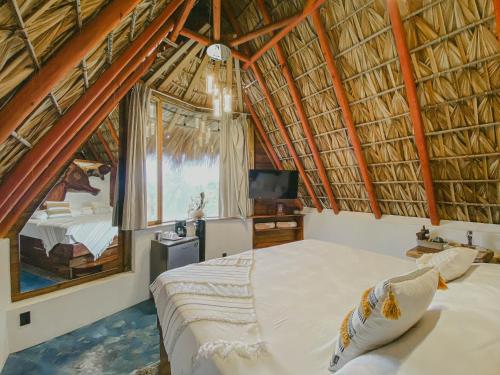 une chambre avec un lit dans un toit de paille dans l'établissement Aldea Kanaloa Hotel Puerto Escondido, à Brisas de Zicatela