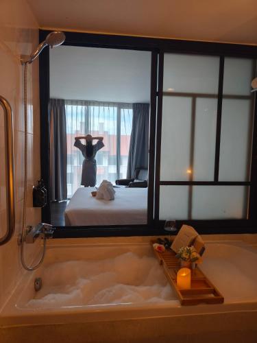 a bathroom with a bath tub with a bed in a room at Art Mai Gallery Nimman Hotel Chiang Mai in Chiang Mai