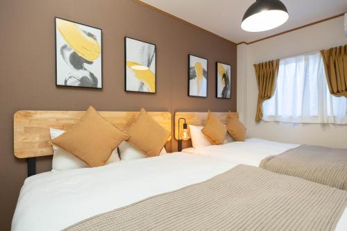 2 letti in una camera da letto con immagini appese al muro di Maison Raffine ad Osaka