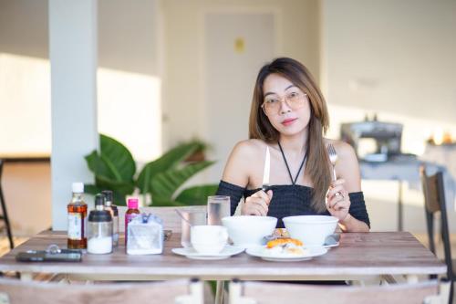 a woman sitting at a table with a plate of food at Baan Kieng Tawan in Khong Chiam