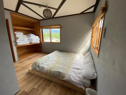 une petite chambre avec un lit et une fenêtre dans l'établissement 一棟貸し宿月灯草津, à Kusatsu