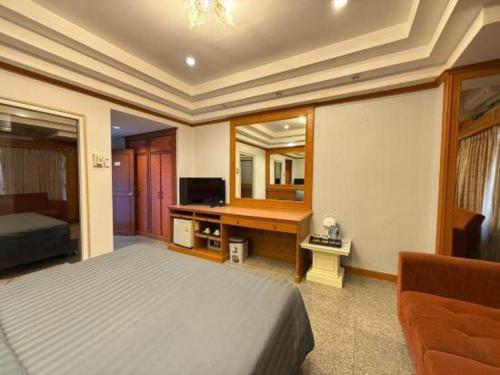 a bedroom with a bed and a desk with a television at New Siya in Maha Sarakham